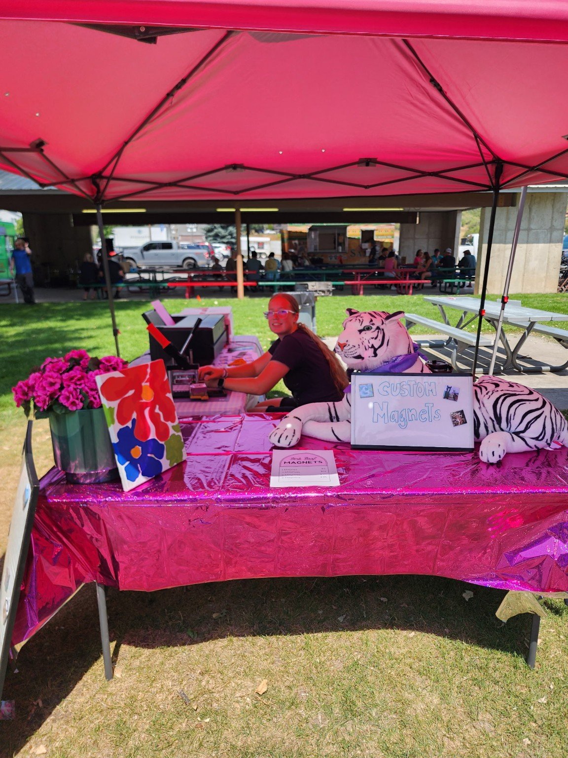 The Pink Roof booth with its bright pink canopy, magnet display, and white stuffed tiger